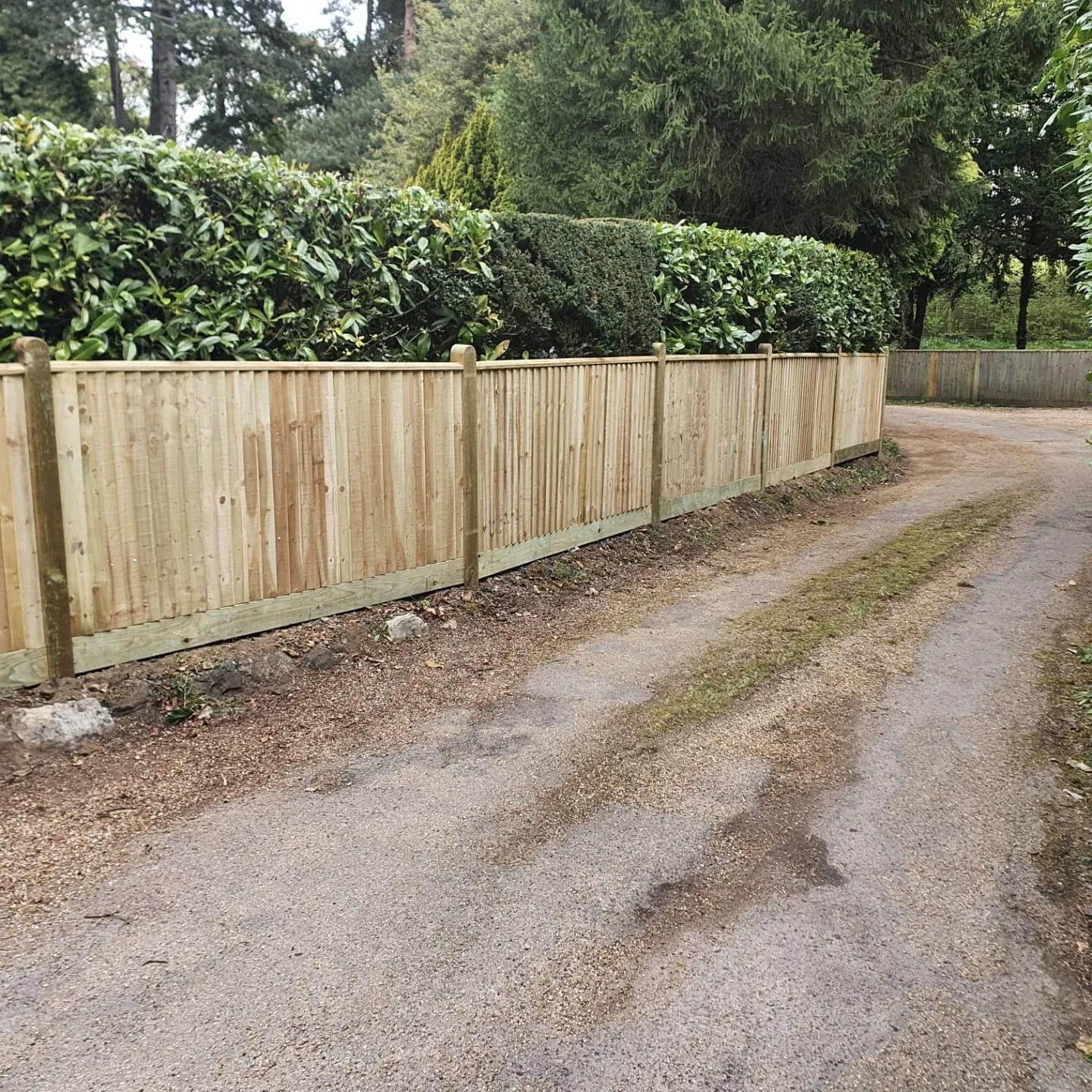 A wooden fence next to a dirt road.
