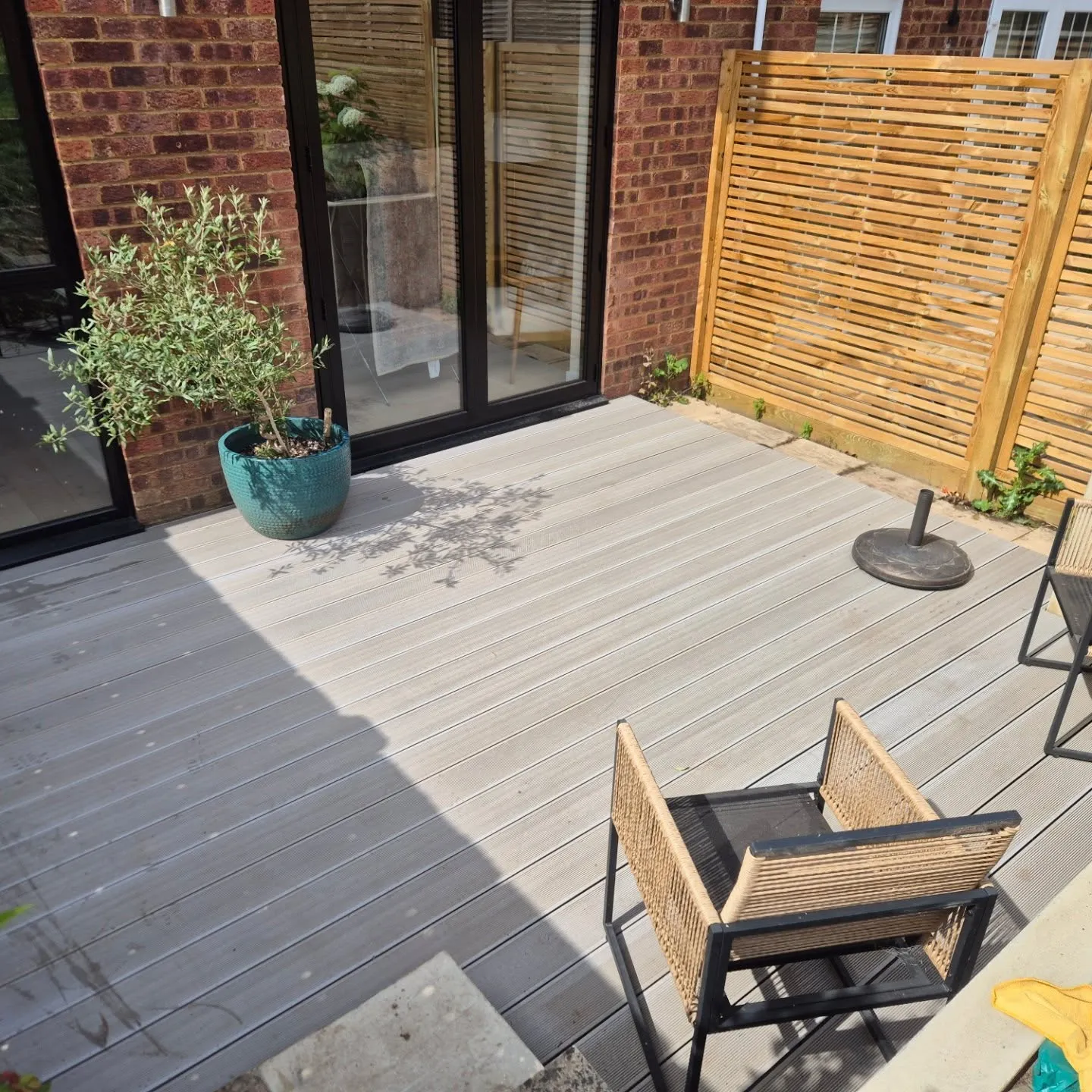 A wooden deck with chairs and a potted plant.