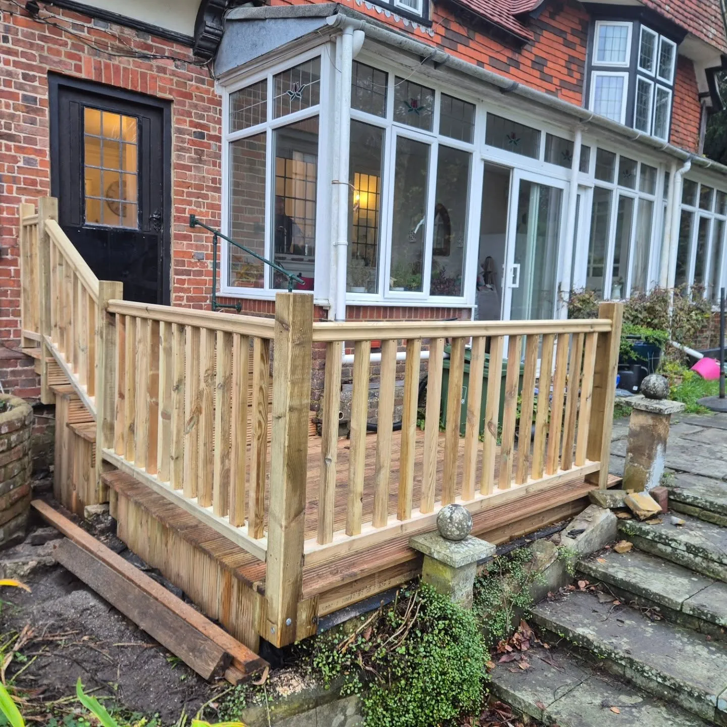 A house with a wooden deck next to a brick building.